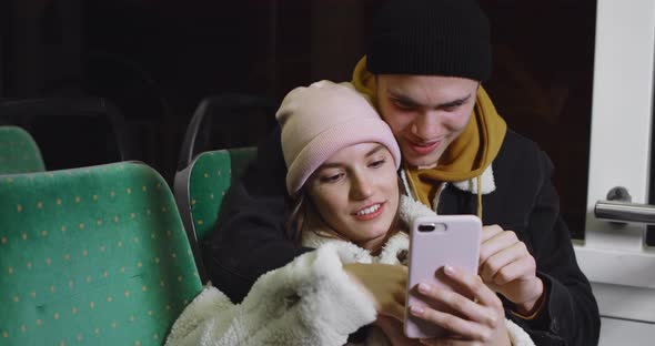 Beautiful Girl Scrolling Smartphone While Leaning on Her Handsome Boyfriend. Cheerful Young Couple