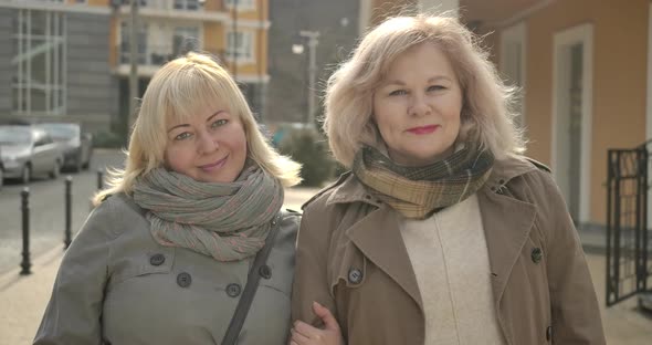 Close-up of Senior Caucasian Women Looking at Camera and Smiling on City Street. Happy Middle-aged