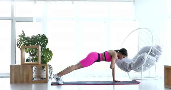 Black woman performing fitness exercises at home.