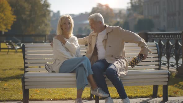Senior Woman Is Delighted with Gift From Husband Siting Together on City Bench