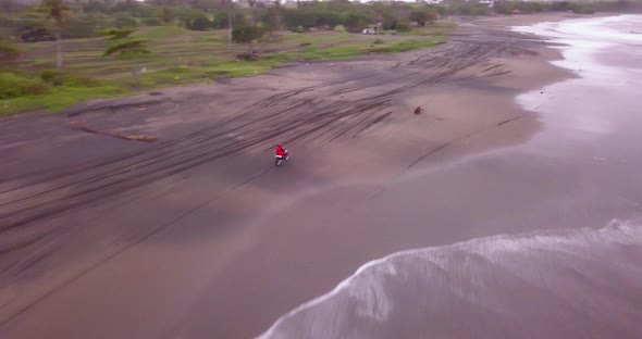 Aerial drone view of a man riding his motocross motorcycle on the beach