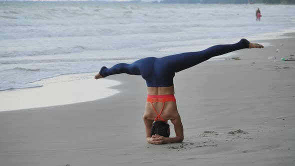 Asian woman is practicing yoga position on the beach.