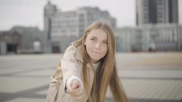 Follow Me Concept. Young Beautiful Woman Stretching Hand To Camera. Turning and Walking Along City