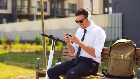 Businessman in Headphones Playing Game on Cell