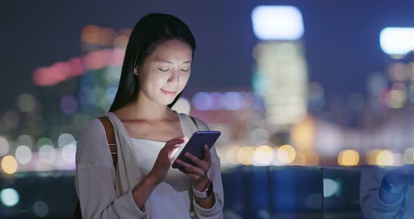 Woman use of mobile phone online in city at night