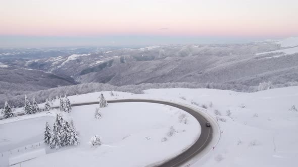 Cars Passing By on Winding Mountain Passage Against Beautiful Winter Landscape