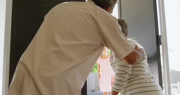 Rear view of senior black couple welcoming children at door in a comfortable home 4k