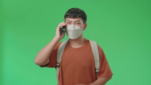 Asian Boy Student Wearing A Mask, Talking On Mobile Phone While Running On Green Screen