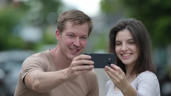 Young Happy Couple Taking Selfie Together in the Streets Outdoors