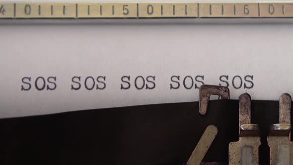 Typing word SOS on retro typewriter. Close up.