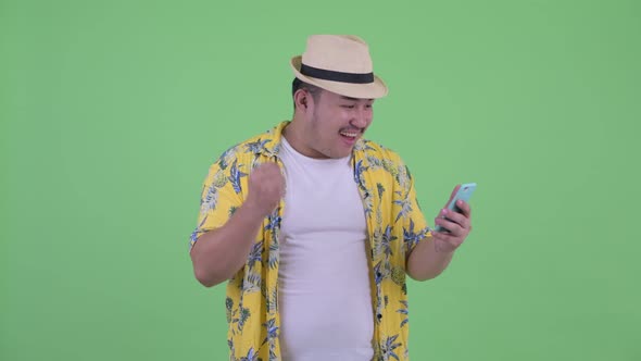 Happy Young Overweight Asian Tourist Man Using Phone and Getting Good News