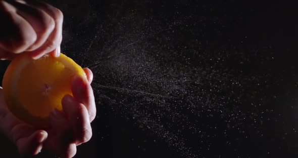 Super Slow Motion squeeze juice from orange close up on a black background