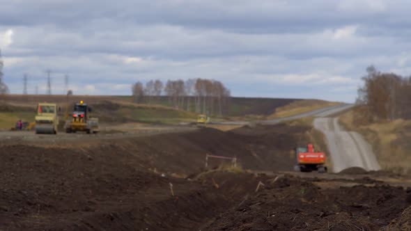 The Worker Looks at the Drawings on the Background of the Road Under Construction