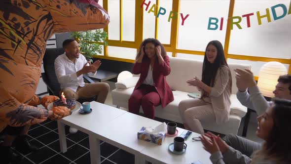 Business woman receiving birthday cake from colleagues at office