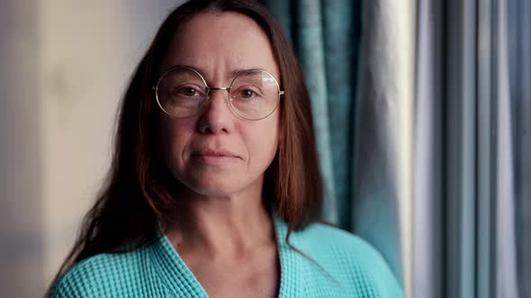 Portrait of an Attractive Woman with Glasses in the Morning at Home in a Bathrobe Standing By the