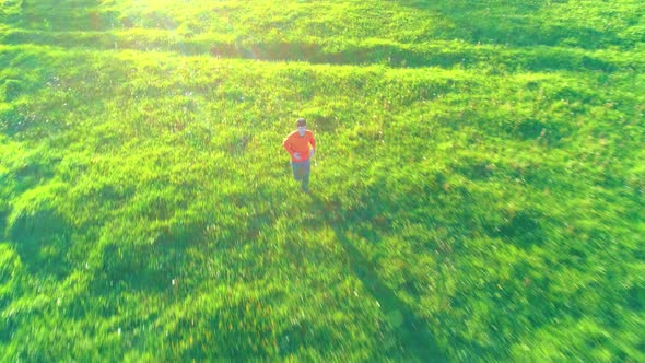 Flight Over Sporty Man Running at Perfect Green Grass Rural Meadow Offroad. Sunset in Mountain