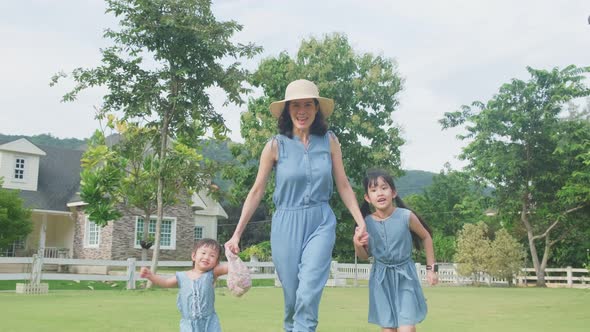 Asian family having fun together at home. Mother holding child hand walking outdoor in garden.