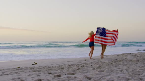 Couple running with American flag at beach 4k