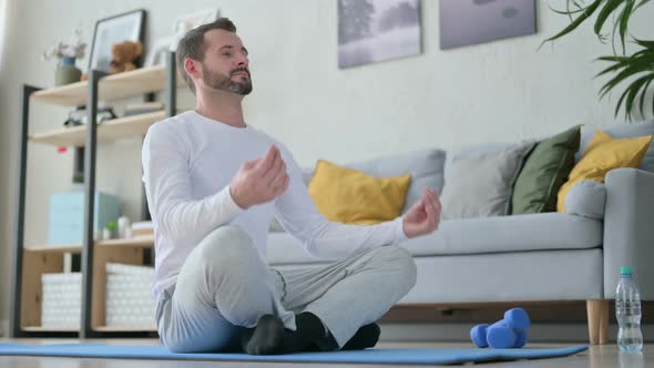 Peaceful Man Meditating on Yoga Mat at Home