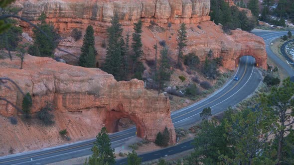 Aerial view of a car driving through one of the Red Cayon road arches near Bryce Canyon