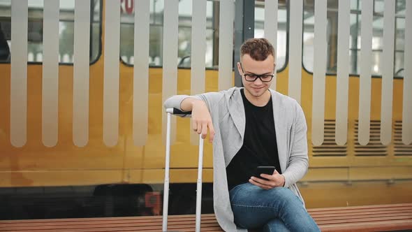 A Man is Sitting at a Public Transport Stop