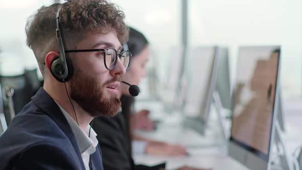 Close Up Portrait of a Technical Customer Support Specialist Talking on a Headset While Working on a