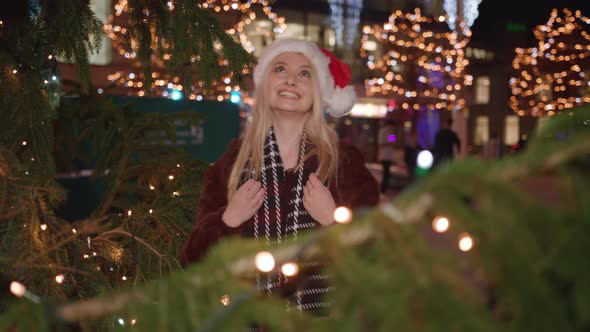 Young lady alks upto Christmas tree and delighted with how it looks