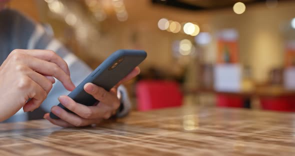 Woman use of mobile phone inside restaurant