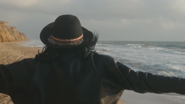 Portrait of Romantic Brunette Woman in Hat and Leather Jacket Walking on the Beach in Autumn at