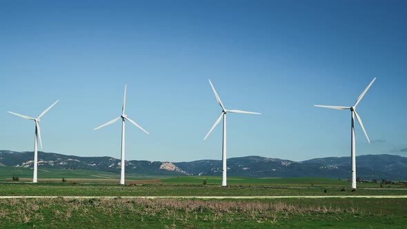 Gimbal Shot of Four Windmills on Background of Mountains in Spain