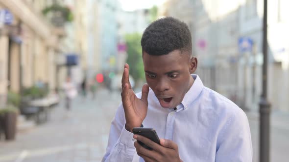 African Man Having Loss While Using Smartphone