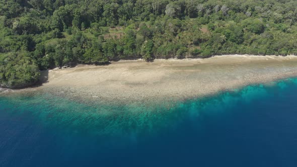 Aerial: flying over tropical Ai island white sand beach Banda Islands Indonesia