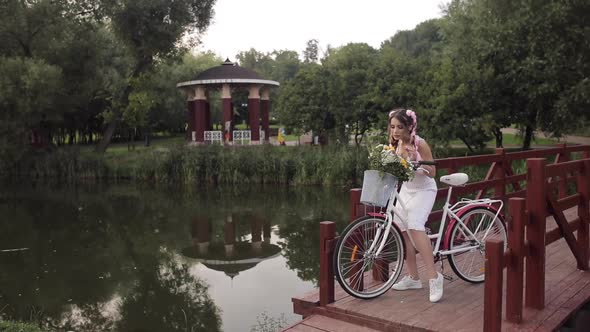 Woman in White Dress Looking at Camera While Riding in Park