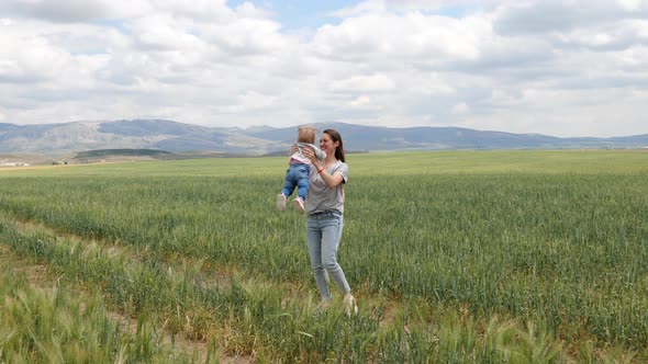 Happy Young Mother Playing Outdoors with Her Little Baby