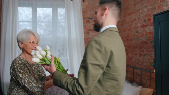 Elderly Caucasian Woman Wearing Eyeglasses Receives a Hug From Her Middleaged Caucasian Son