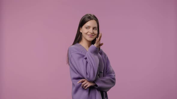 Portrait of a Model with Natural Beauty Coquettishly Waves Hello and Makes Hand Gesture to Come Here