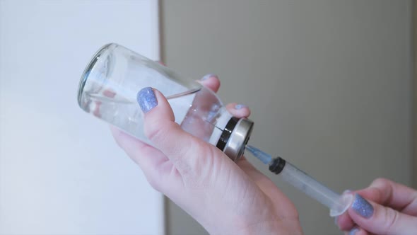 A Young Girl Dials Medicine Into a Syringe