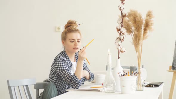 Beautiful Blond Girl with Bun in Stylish Casual Clothes Choosing a Pencil