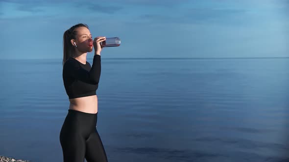 Relaxed Fitness Woman Drinking Water From Bottle After Outdoor Workout