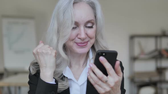 Senior Businesswoman Celebrating Success on Smartphone