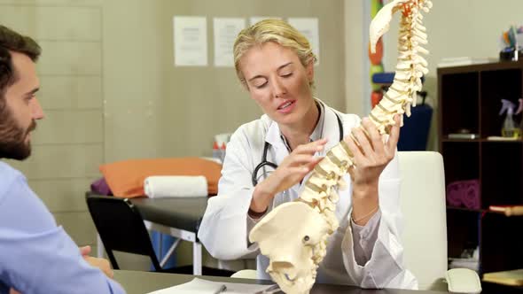 Physiotherapist explaining spine model to patient