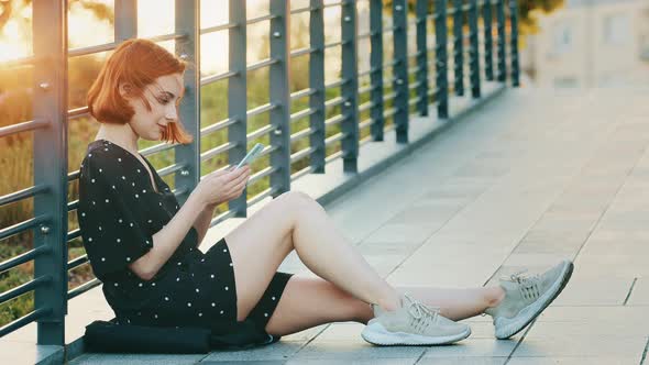 Attractive Young Girl Teenager Pretty Redhead Woman with Short Hair Sit on City Bridge Rest Outdoors