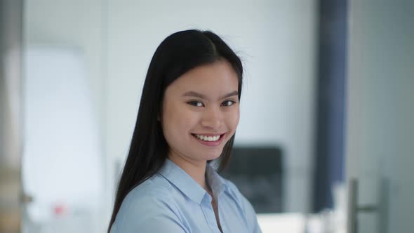 Close Up Portrait of Young Positive Asian Lady Employee Turning Face to Camera and Laughing Slow