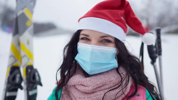 Headshot of Joyful Smiling Young Woman in Covid Face Mask and Christmas Hat Looking at Camera