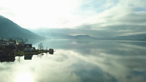 Very beautiful drone shot over the lake of Zug. The lake is extremly reflective, the sun is setting.