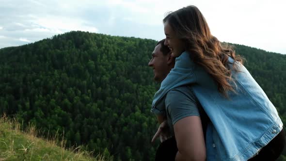 Happy Young Men Giving Piggyback Ride To Women in the Mountain. Young Couple Having Fun Outdoors.