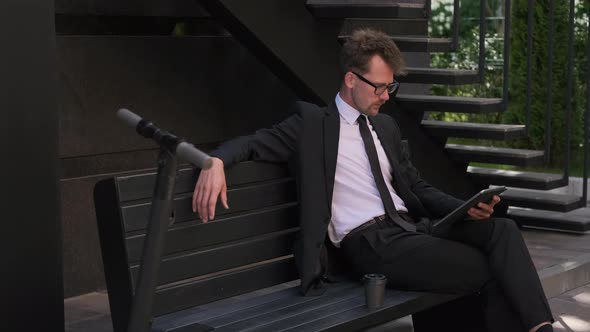 Male Working Using Video Call on Tablet While Sitting on Bench