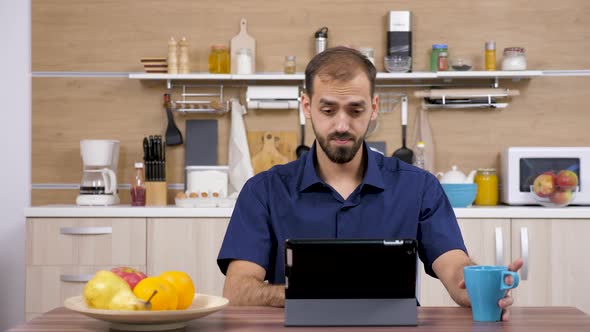 Man in the Kitchen Looking at Digital Tablet PC