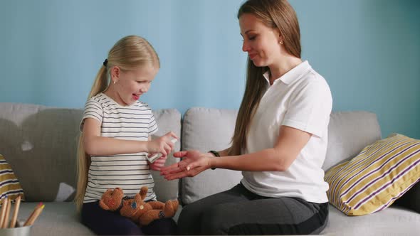 Small Girl Cleans Hands To Her Mom With Antiseptic Spray