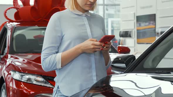 Woman Using Her Smart Phone at the Car Dealership Salon